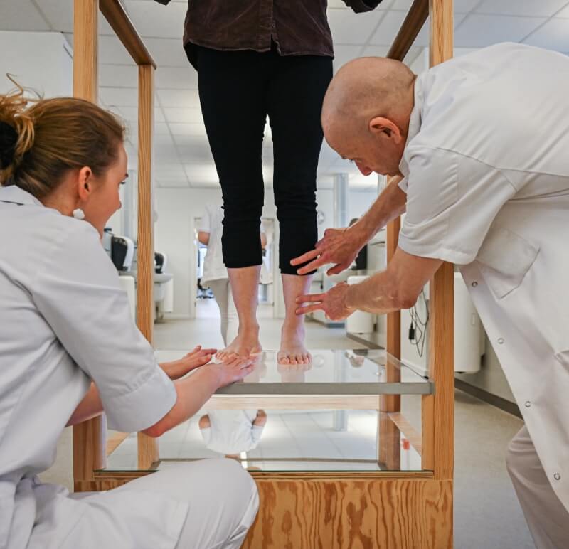 Underviser og elev fra fodterapeutuddannelsen undersøger en patients fodstilling